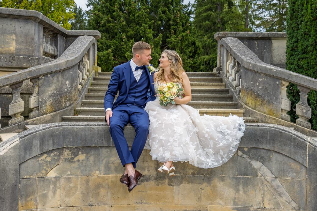 Hochzeitspaar sitzt nebeneinander und schaut sich in die Augen.